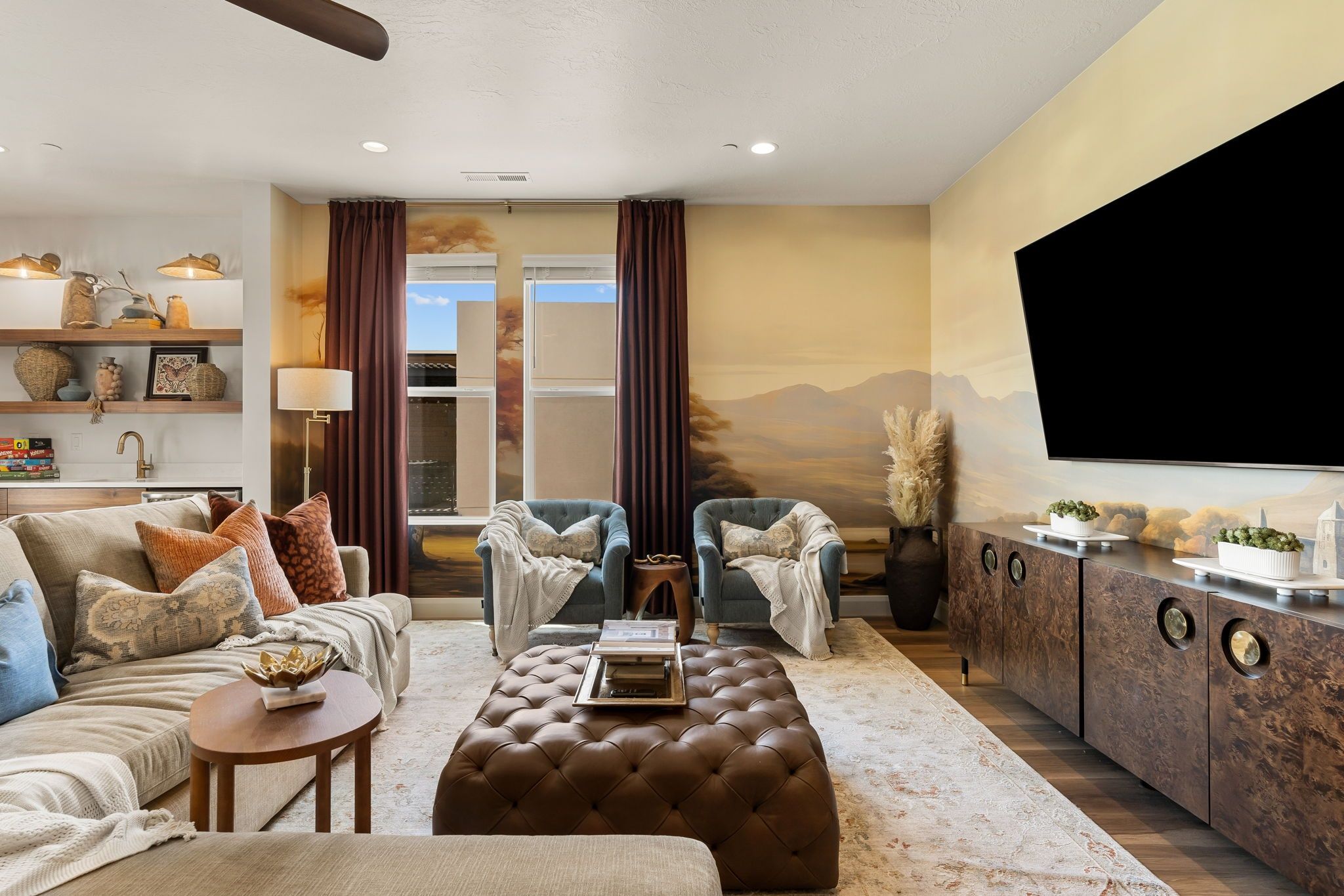 A modern living room with a sofa, two armchairs, a coffee table, and a TV.