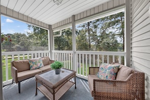 A covered porch with wicker furniture, a glass coffee table, and a potted plant. - 6e Palmetto Paradise 2 Bedroom Condo (Pawleys Island)