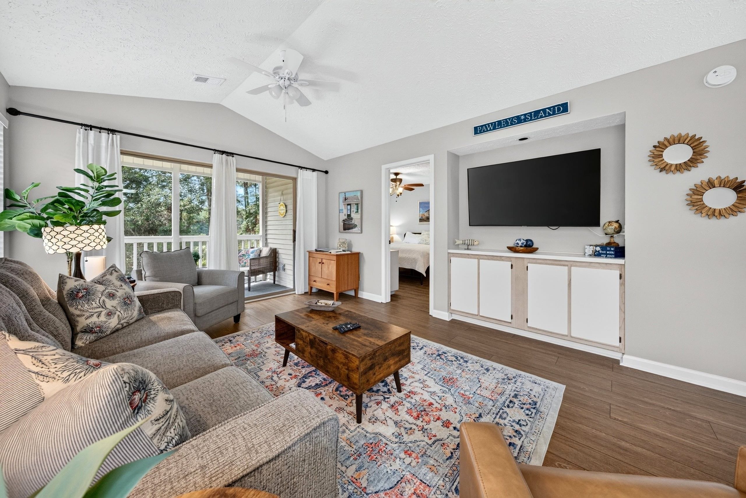 A spacious living room with a large sofa, a coffee table, and a television mounted on a white wall.