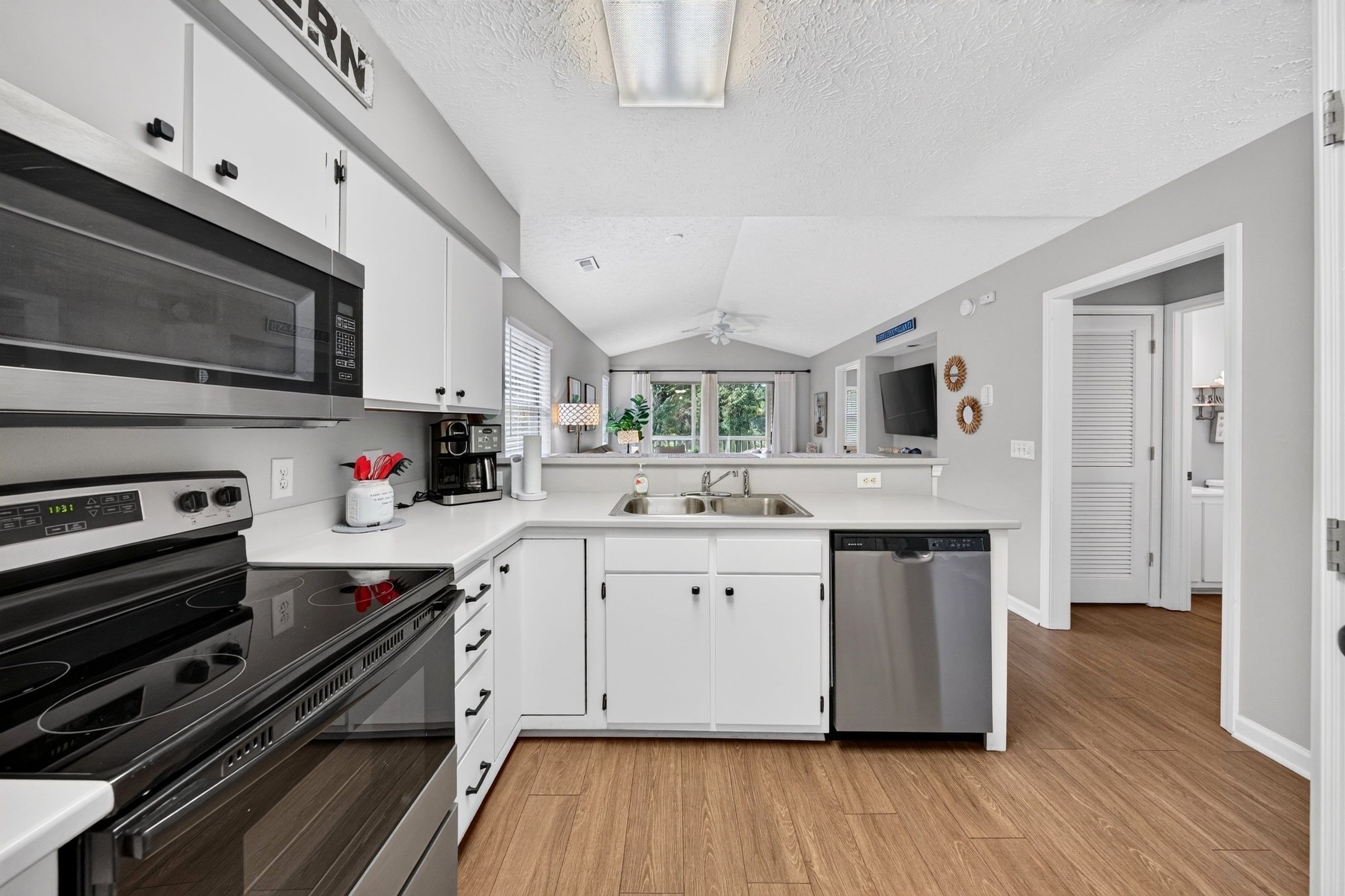 A modern kitchen with white cabinets, a stainless steel dishwasher, and a black microwave.