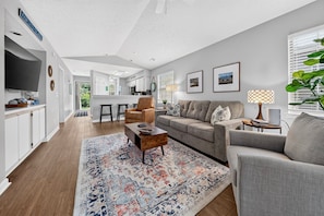 A modern living room with a grey sofa, a coffee table, and a patterned rug. - 6e Palmetto Paradise 2 Bedroom Condo (Pawleys Island)