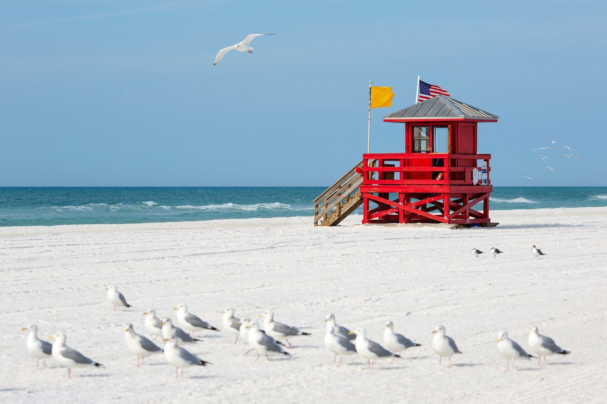 A lifeguard tower with a flag on a beach.