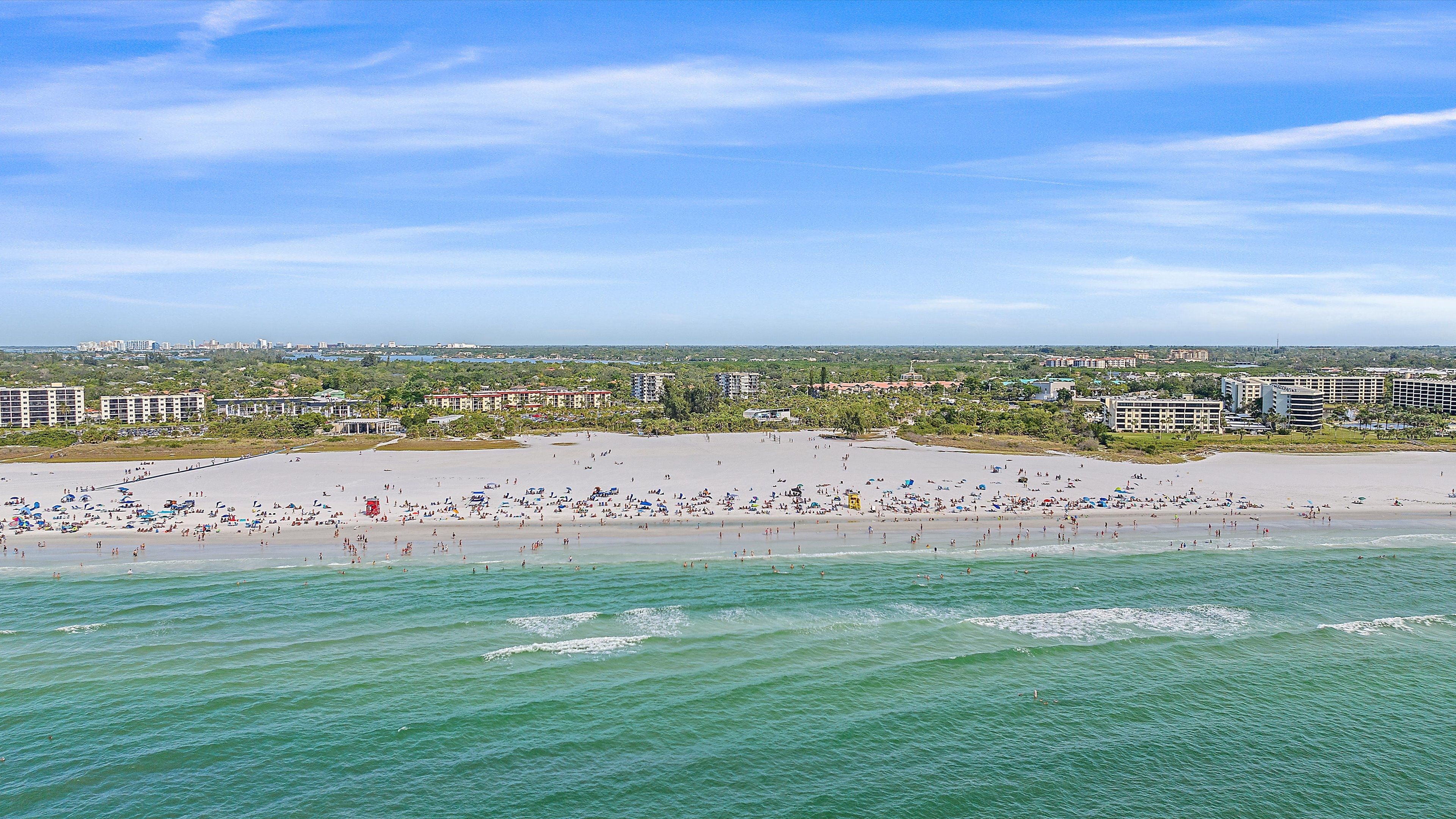 A beach with people, buildings, and a clear sky.