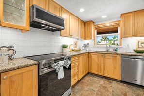 A kitchen with wooden cabinets, a stainless steel range, and a dishwasher. - Siesta Time 4 Bedroom Home (Siesta Key)