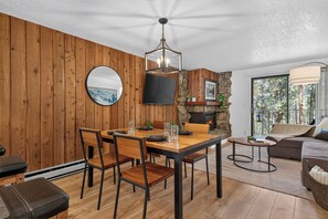 A dining area with a wooden table and chairs, a fireplace, and a view of the outdoors. - Beaver Village unit 1811 renovated 2 bedroom, views from private deck, clubhouse (Winter Park)