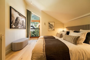 Ein Hotelzimmer mit Bett, einer Bank, einem Gemälde und Blick ins Freie.