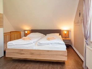 A double bed with white linens in a room with wooden flooring and two bedside lamps. - 3.6/t3 Holiday Home Park \"freesenbruch\" (Zingst)
