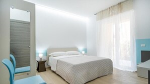 Quarto com cama, cadeira, mesa de cabeceira e janela com cortinas.
