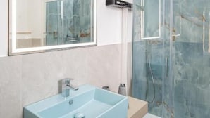 Um banheiro moderno com pia retangular, box de vidro e um espelho grande.