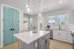A modern kitchen with a central island, white cabinetry, and a blue door. - Luxury Pet Friendly Waterfront Home Private Pool & Dock in Resort Community Manatee Dreams at Hunters Point (Cortez)