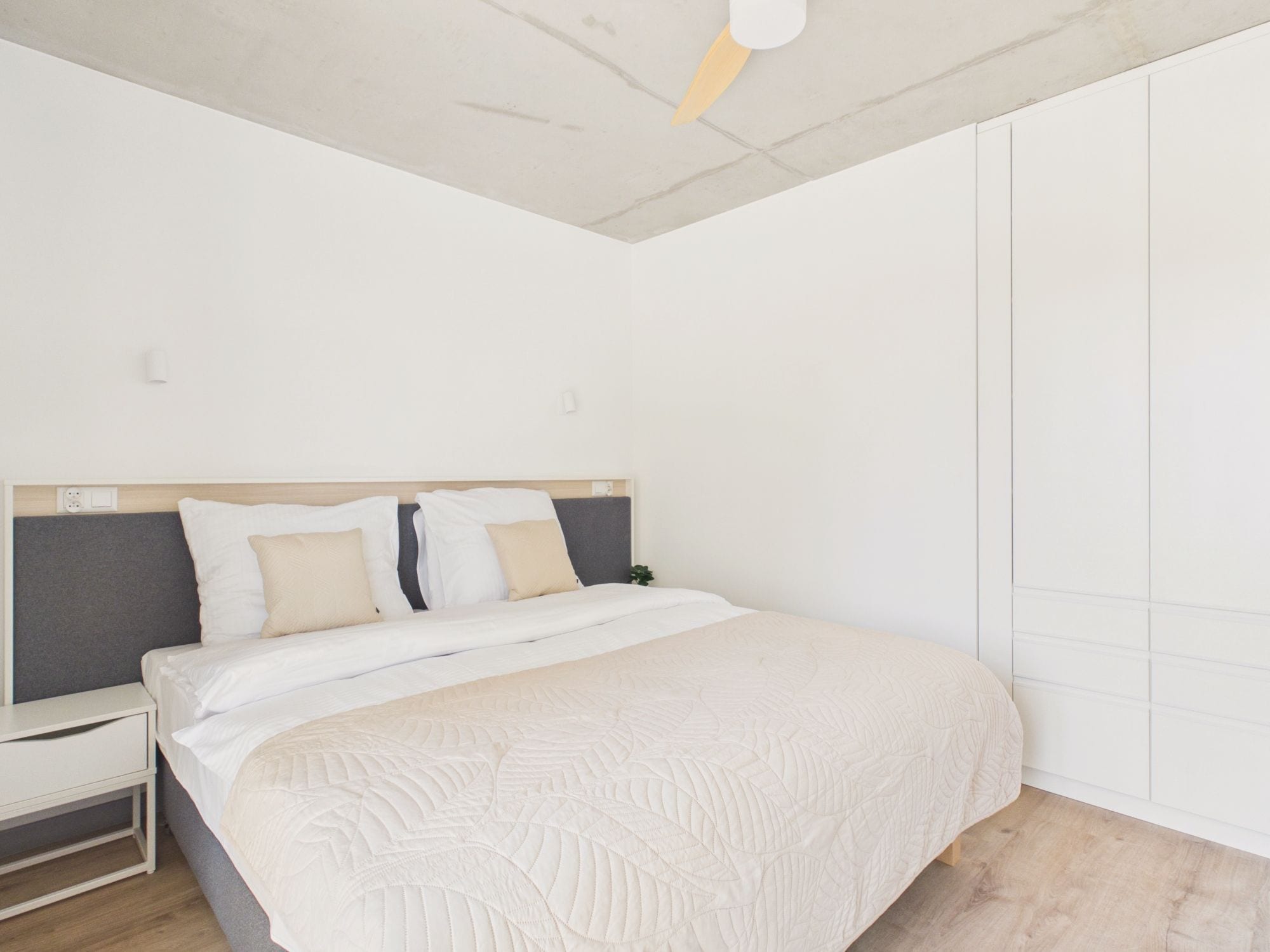 A bedroom with a bed, bedside table, and a nightstand.