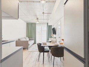 A modern kitchen with a dining area, a sofa, and a view of the city. - NanoApart by Solarento (Warszawa)