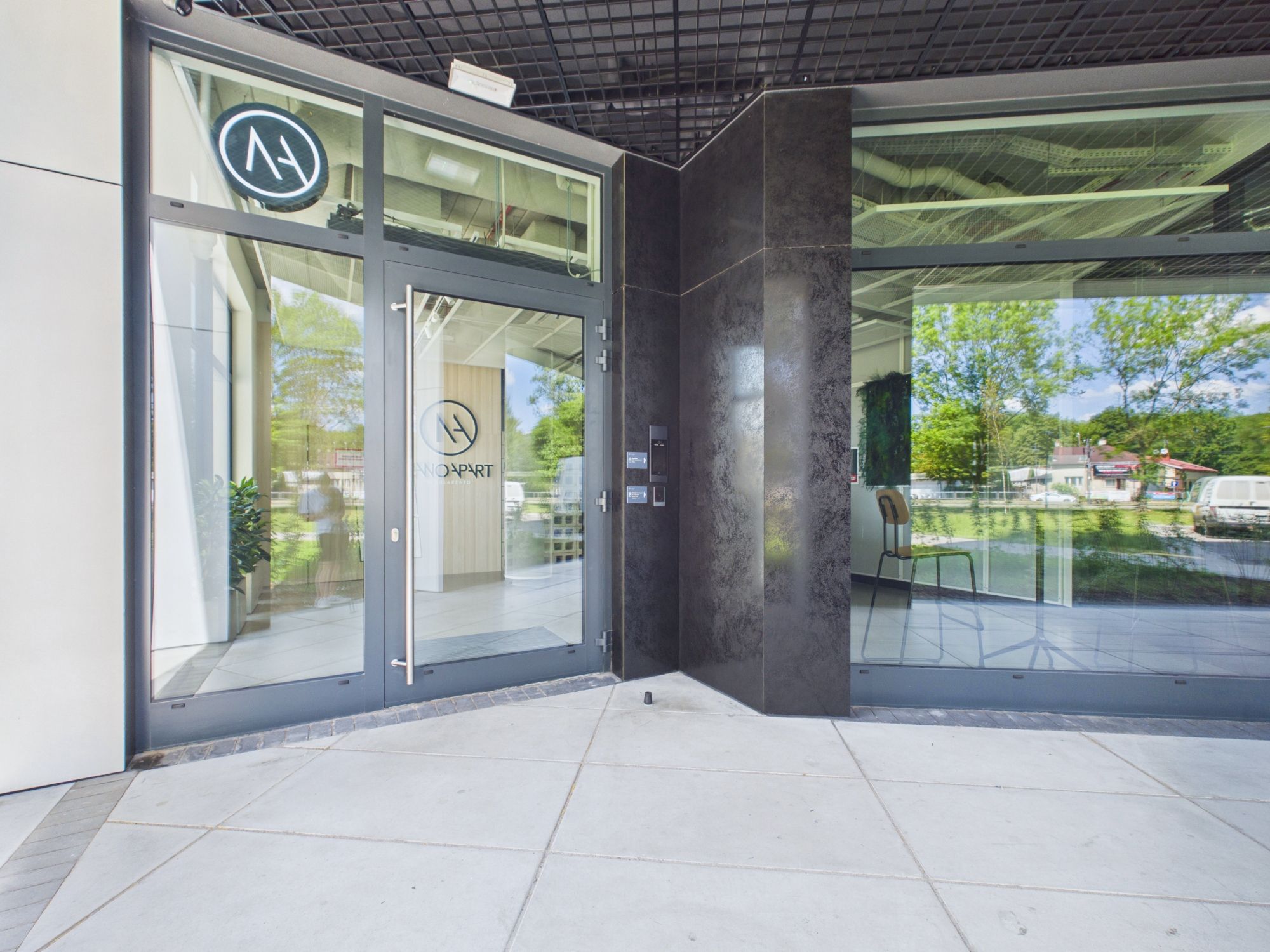 A modern building entrance with glass doors, a logo, and a clear view of the outside.