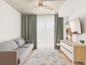 A modern living room with a grey sofa, wooden desk, and a ceiling fan. - NanoApart by Solarento (Warszawa)