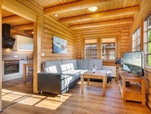 A cozy cabin interior with a wooden ceiling, a sofa, a television, and a kitchen area. - Holiday Home in Sassnitz/rugen With Sauna (Sassnitz)