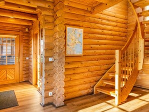 A wooden cabin interior with a staircase, a wall-mounted map, and a door with a window. - Holiday Home in Sassnitz/rugen With Sauna (Sassnitz)