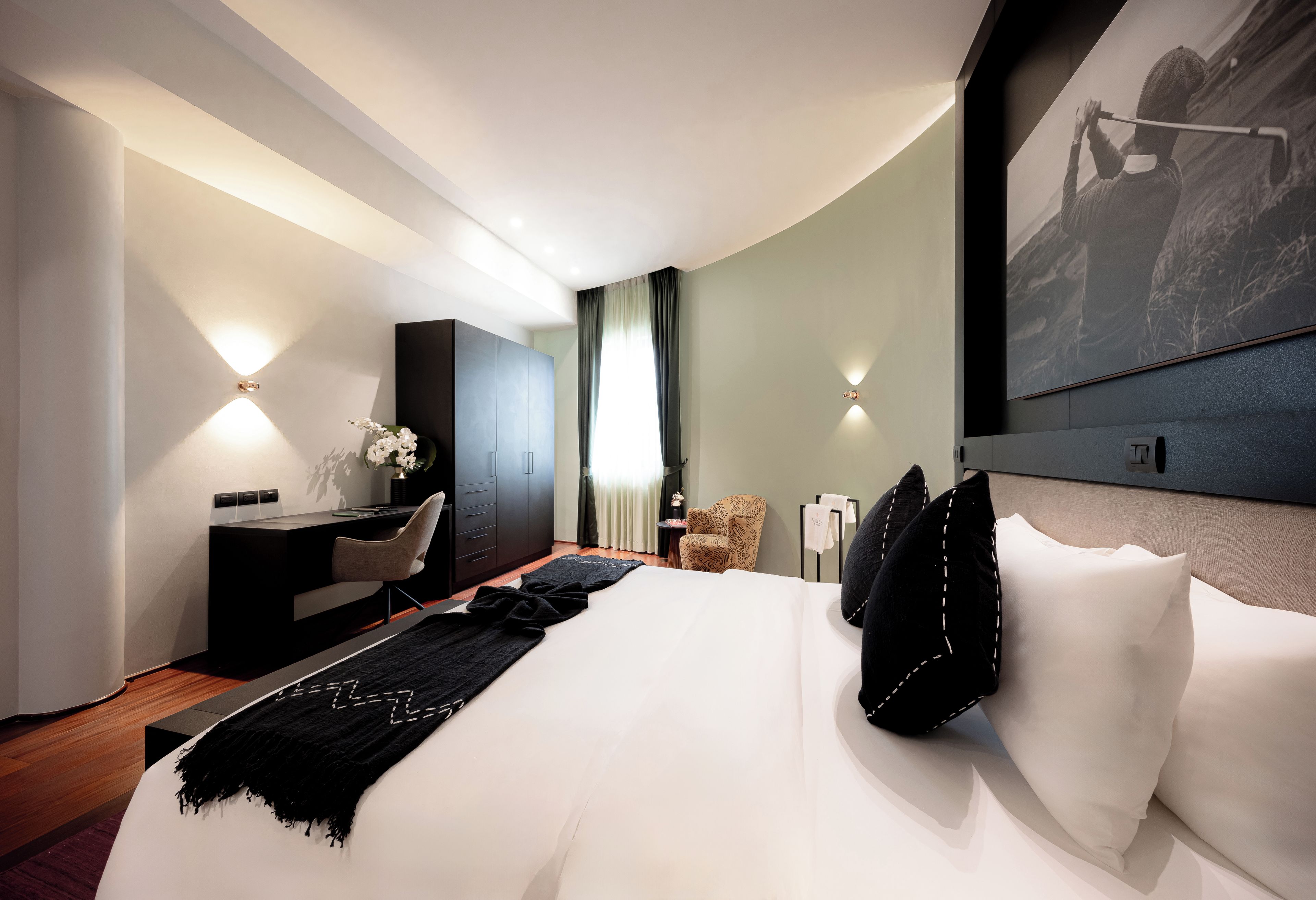 Una habitación de hotel moderna con una cama grande, un escritorio, una silla y un armario.