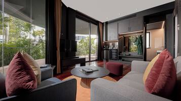 A modern living room with a large TV, comfortable seating, and a view of the outdoors.