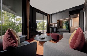 Een moderne woonkamer met een grote televisie, comfortabele zitplaatsen en uitzicht op de omgeving.