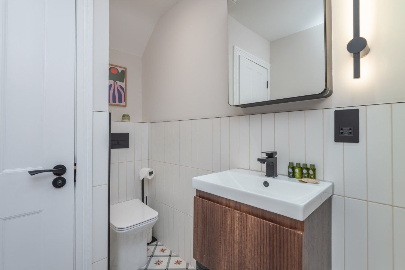 A bathroom with a white sink, a toilet, and a mirror.