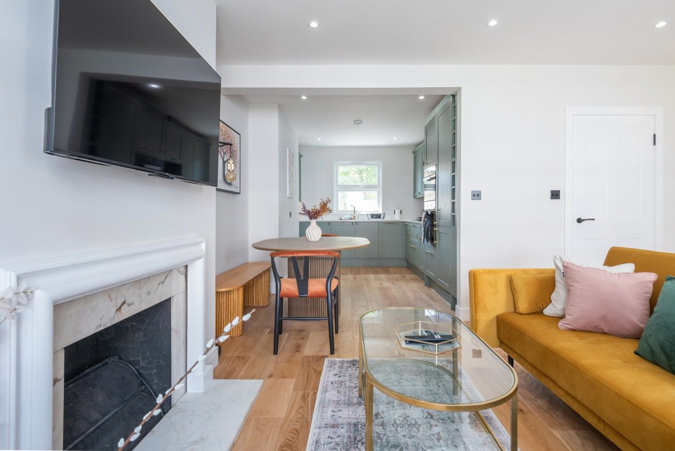 A modern living room with a fireplace, a glass coffee table, and a sofa with cushions.