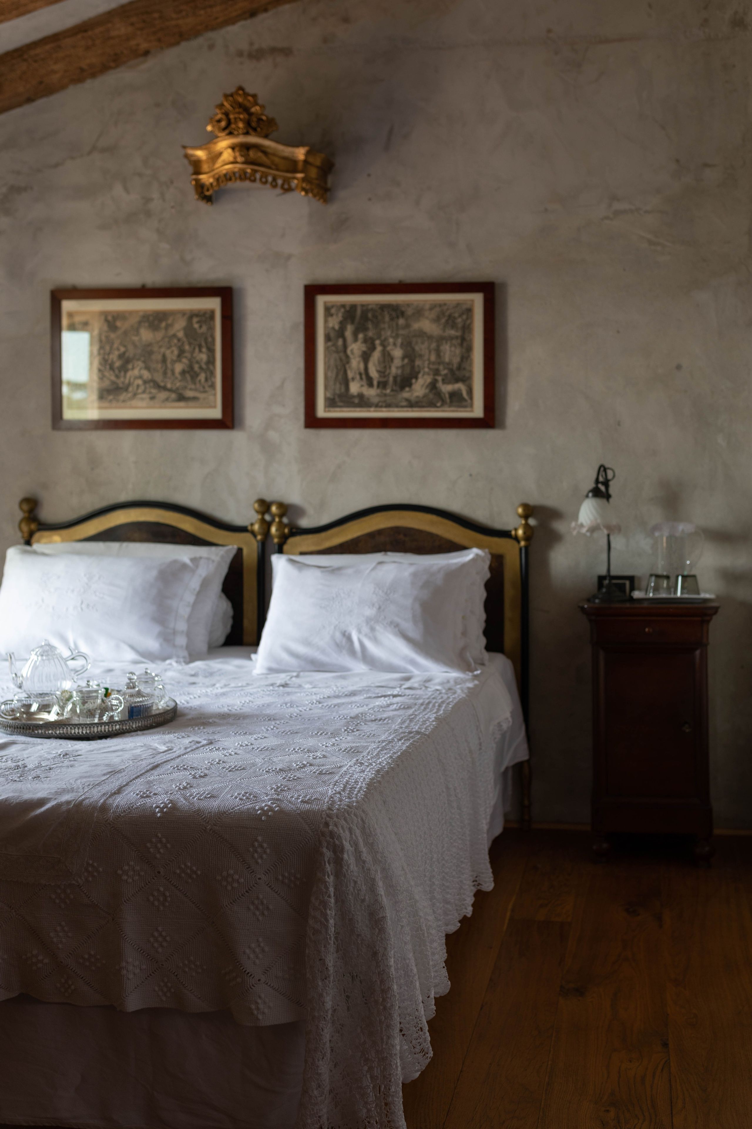 A bedroom with a wooden bed, a nightstand, and two framed pictures on the wall.