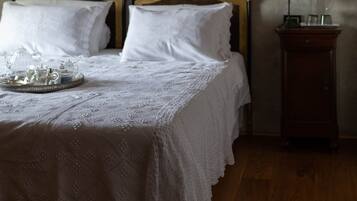 A bedroom with a wooden bed, a nightstand, and two framed pictures on the wall.