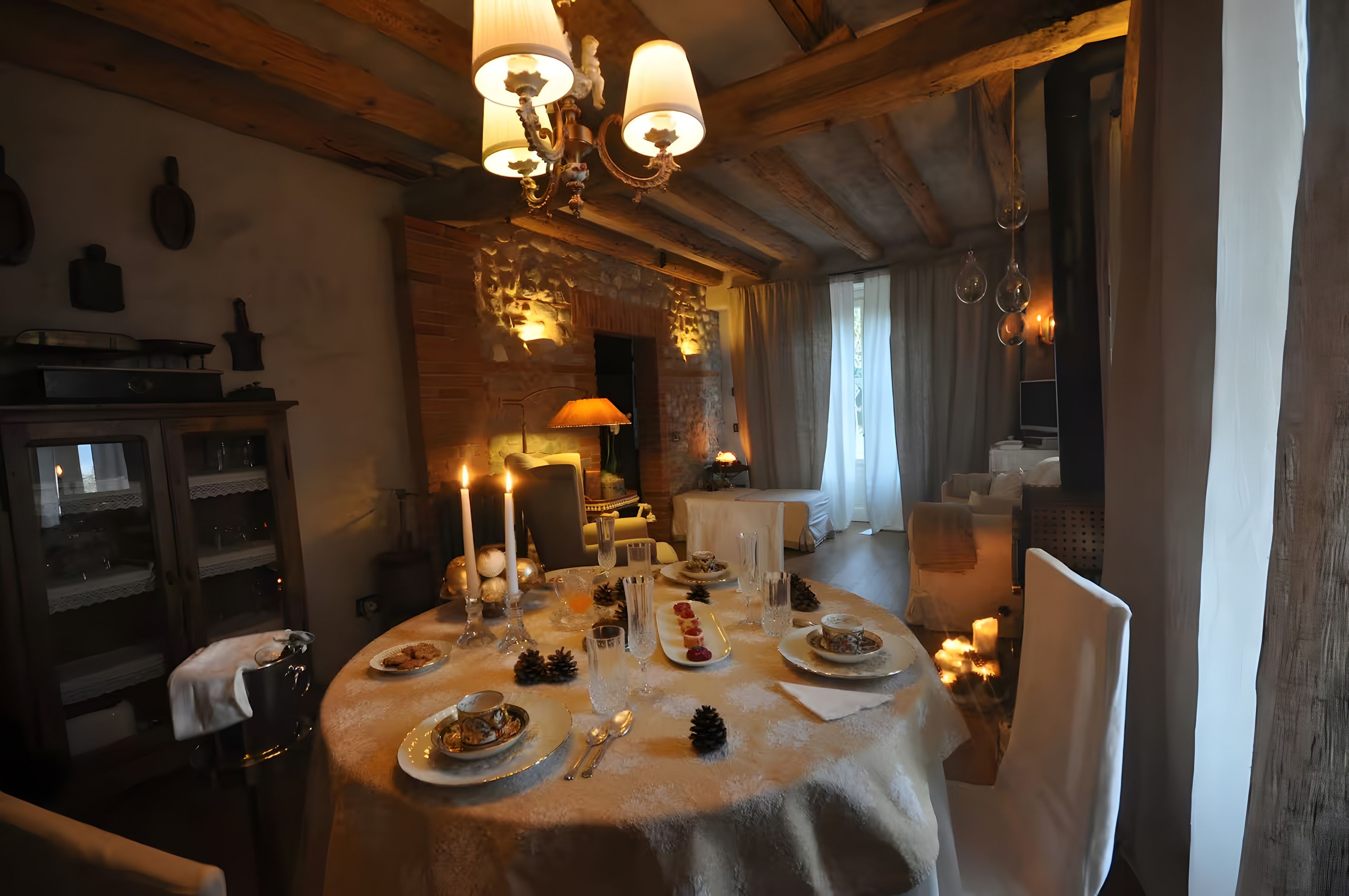 Ein gemütlich beleuchteter Essbereich mit einem runden Tisch, gedeckt für eine Mahlzeit, Kerzen und einem Chandelier.