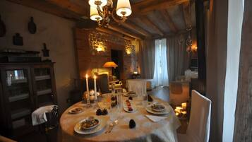 Ein gemütlich beleuchteter Essbereich mit einem runden Tisch, gedeckt für eine Mahlzeit, Kerzen und einem Chandelier.