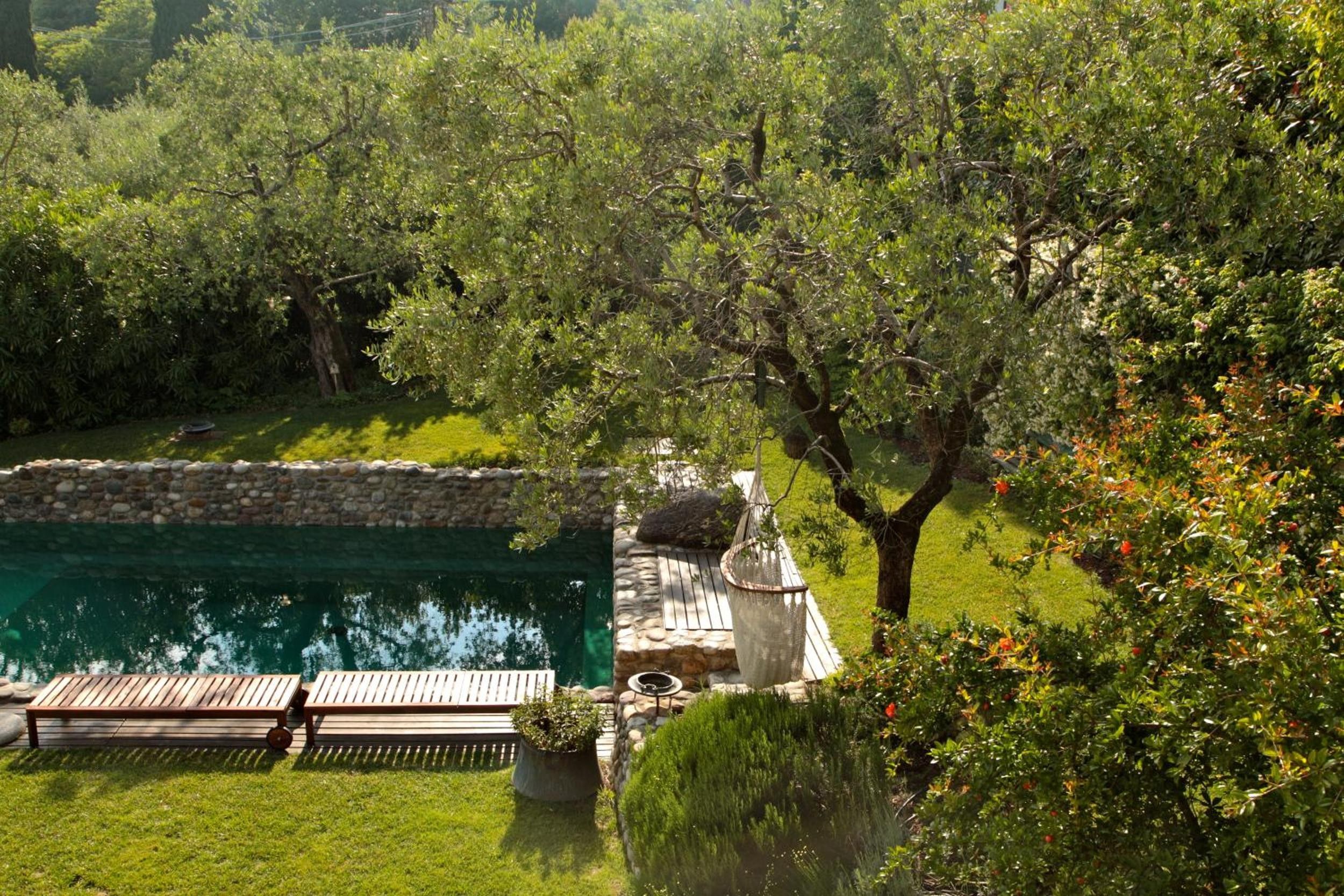 Ein Poolbereich mit Steinmauer, Holzterrasse und einer Pergola.