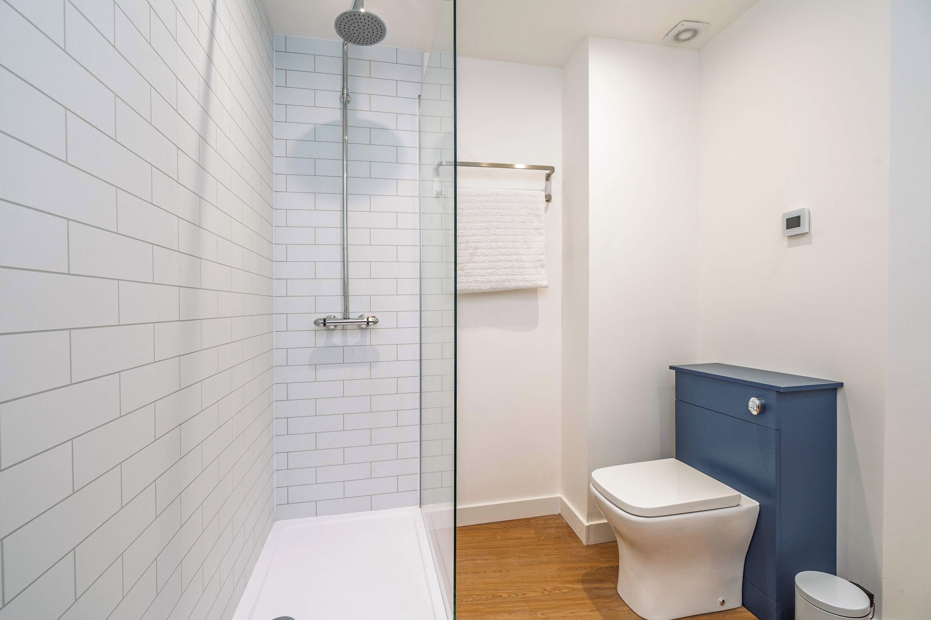 Une salle de bain avec une douche, des toilettes et un meuble de rangement.