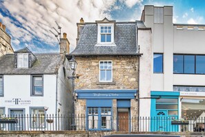 A traditional stone building with a blue storefront, a visible telephone number, and a sign indicating 'West Terrace'. - Cozy Studio at The Brewery (Queensferry)