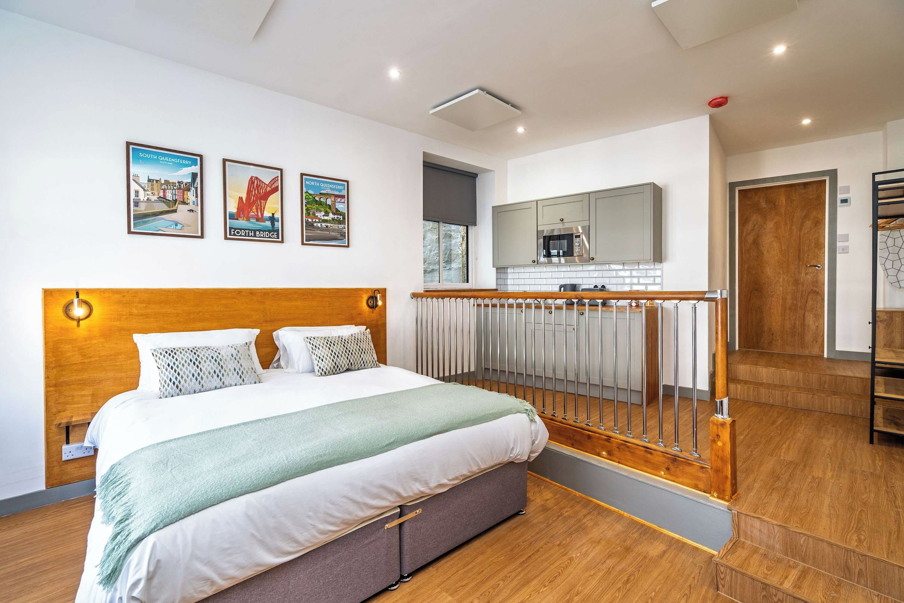 Een hotelkamer met een bed, uitzicht op de stad en een balkon met een kitchenette.