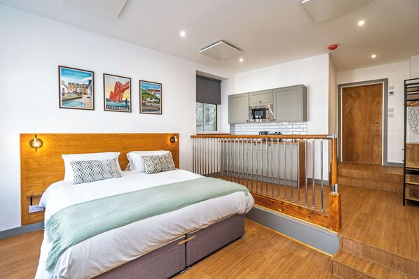Hotellihuone, jossa on sänky, näköala kaupunkiin ja parveke, jossa on pieni keittiötila.