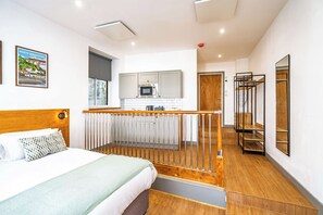 Ein modernes Hotelzimmer mit Bett, einer Küchenzeile, einer Treppe und Blick auf die Stadt.