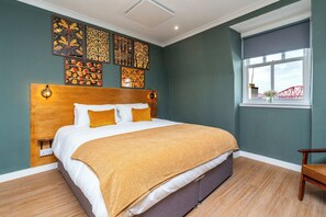 Une chambre d’hôtel avec un grand lit, une tête de lit en bois et des œuvres d’art accrochées aux murs.
