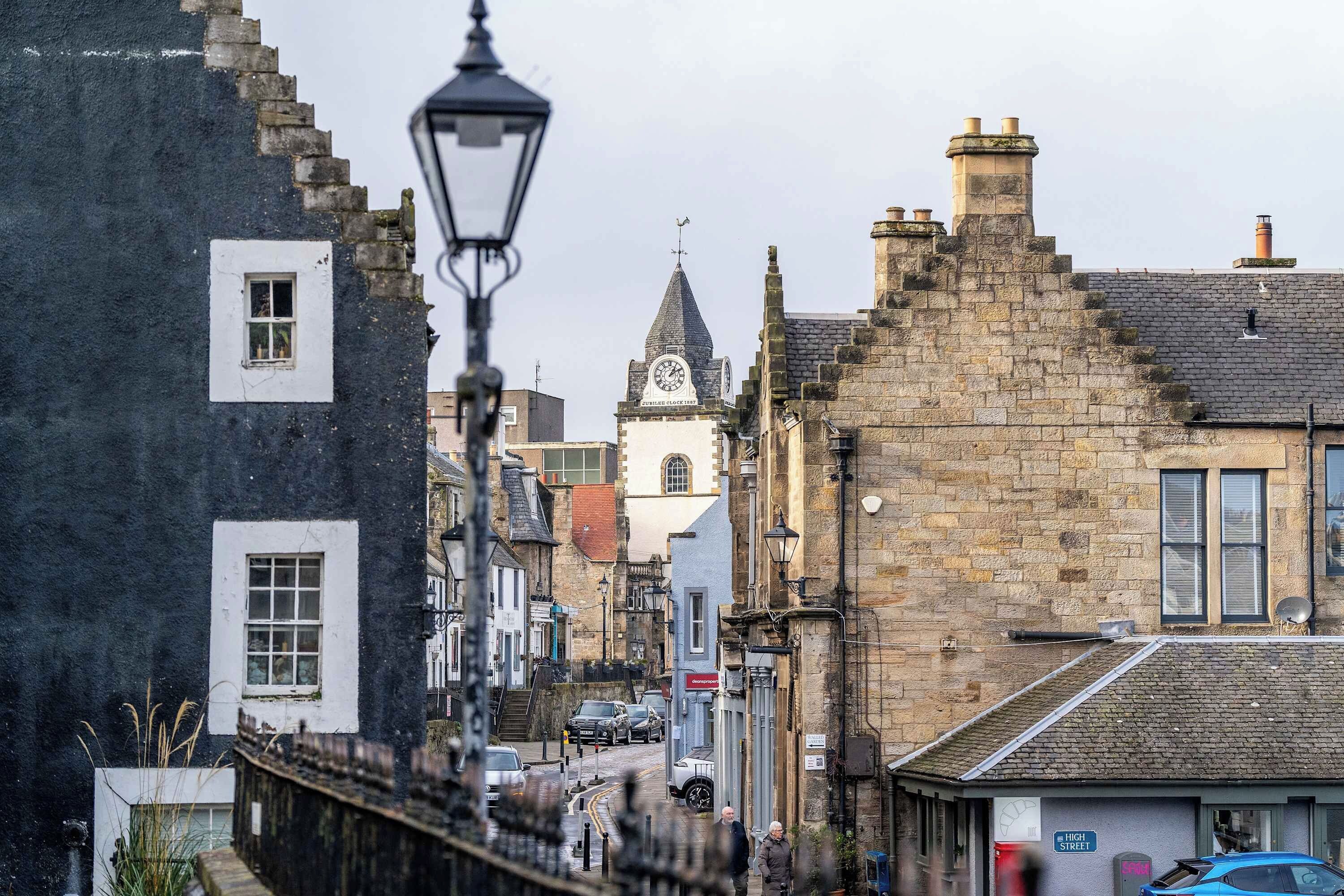 A street view with traditional stone buildings, a clock tower, and a clear sky.