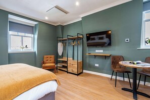 A room with a bed, a chair, a table, a TV, and a window. - Cozy Boutique Studio at The Brewery (Queensferry)