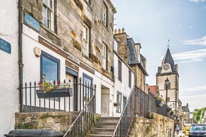 Un bâtiment historique doté d’une tour horlogée, d’une entrée bien visible et d’une enseigne indiquant « The G-ROOM », ce qui correspond à un numéro de pièce.