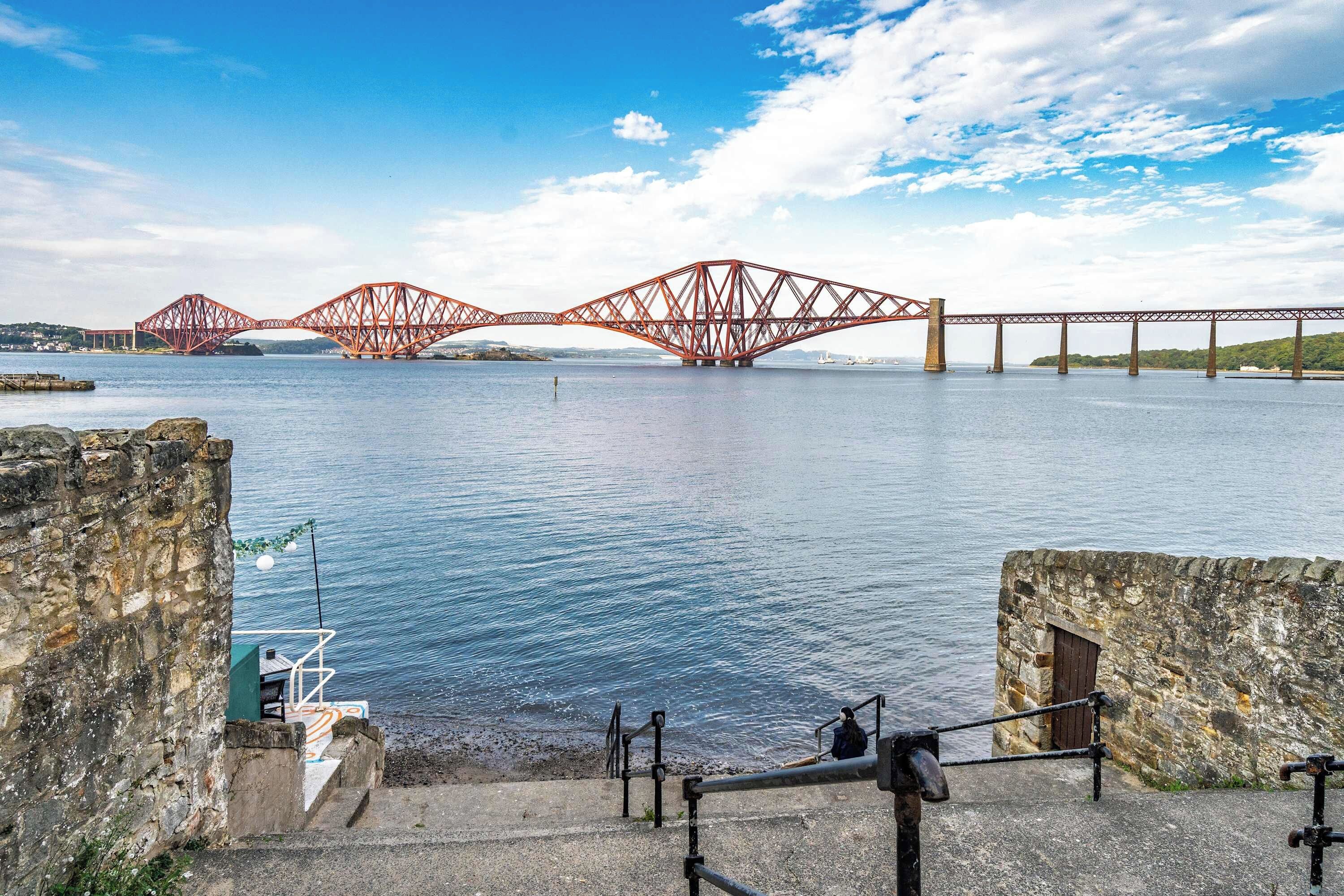 A coastal view with a prominent red bridge structure spanning across the water.