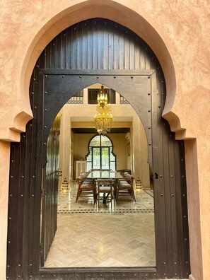 A large wooden door with a chandelier, leading to a room with a dining table and chairs. - Elegant 3-bedroom Riad with AC perfect for relaxing stays (Marrakech)