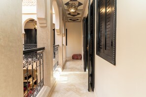 A corridor with arches, a patterned rug, and a bed with a patterned cover. - Elegant 3-bedroom Riad with AC perfect for relaxing stays (Marrakech)