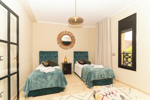 A bedroom with two beds, a hanging light fixture, a mirror, and a window with curtains. - Elegant 3-bedroom Riad with AC perfect for relaxing stays (Marrakech)