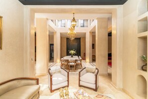 A spacious interior with a central dining area, high ceilings, and a chandelier. - Elegant 3-bedroom Riad with AC perfect for relaxing stays (Marrakech)