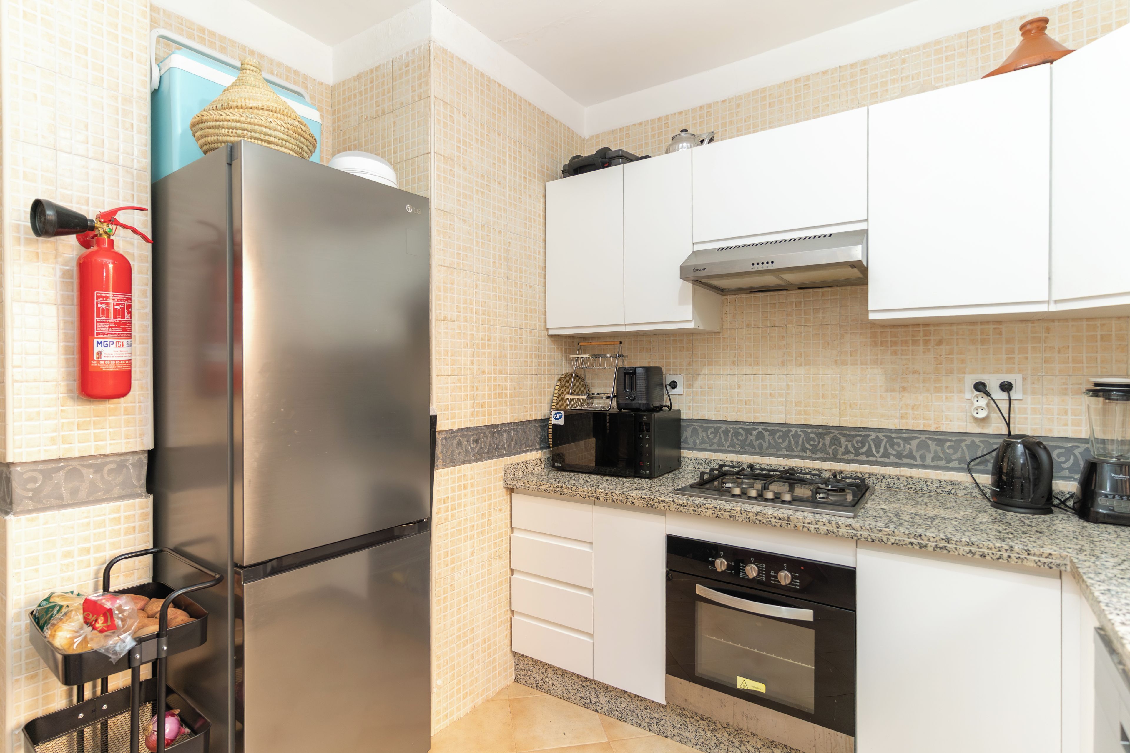 Una cocina con un refrigerador de acero inoxidable, cafetera, tostadora y lavavajillas.