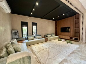 A modern living room with a sectional sofa, a flat-screen TV, and a patterned rug. - Elegant 3-bedroom Riad with AC perfect for relaxing stays (Marrakech)