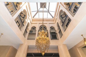 A grand interior with a large chandelier, arched windows, and intricate metal railings. - Elegant 3-bedroom Riad with AC perfect for relaxing stays (Marrakech)