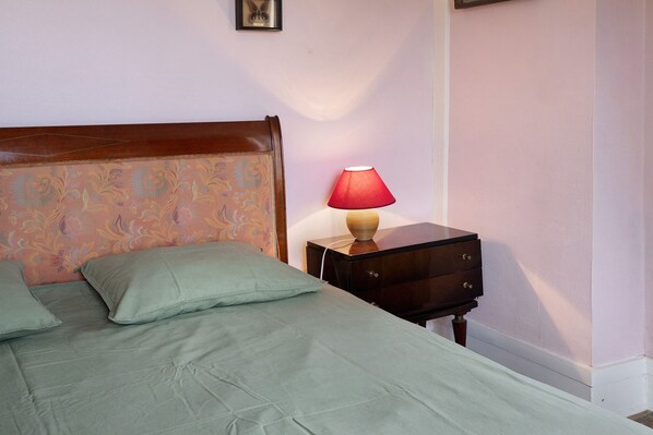 A bed with a headboard, a bedside table with a lamp, and a wall-mounted picture. - Cottage “La Cour Mare” with Private Pool, Terrace, and Wi-Fi (Crouttes)
