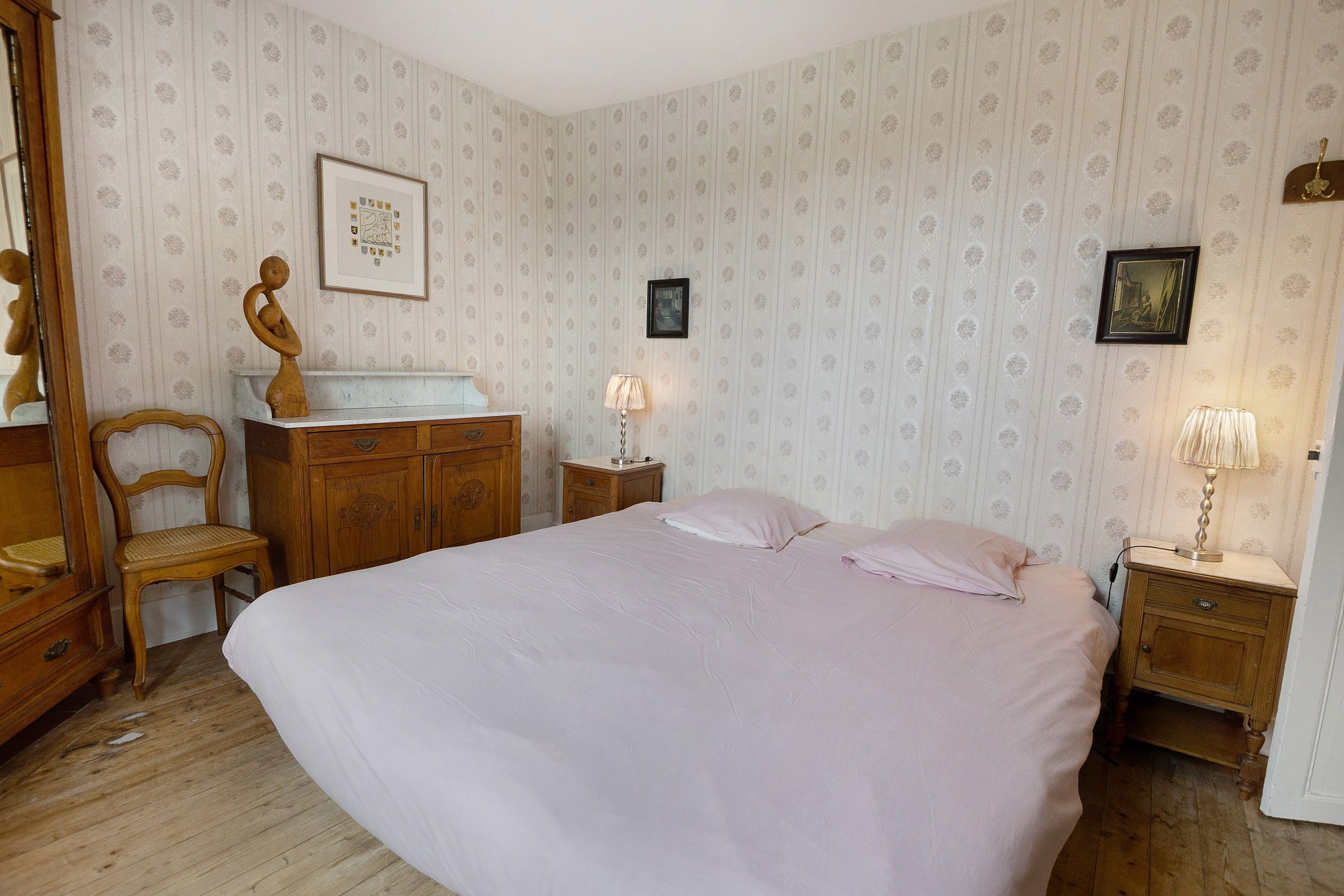 Un dormitorio con una cama grande, muebles de madera y papel tapiz estampado.