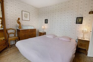 Un dormitorio con una cama grande, muebles de madera y papel tapiz estampado.